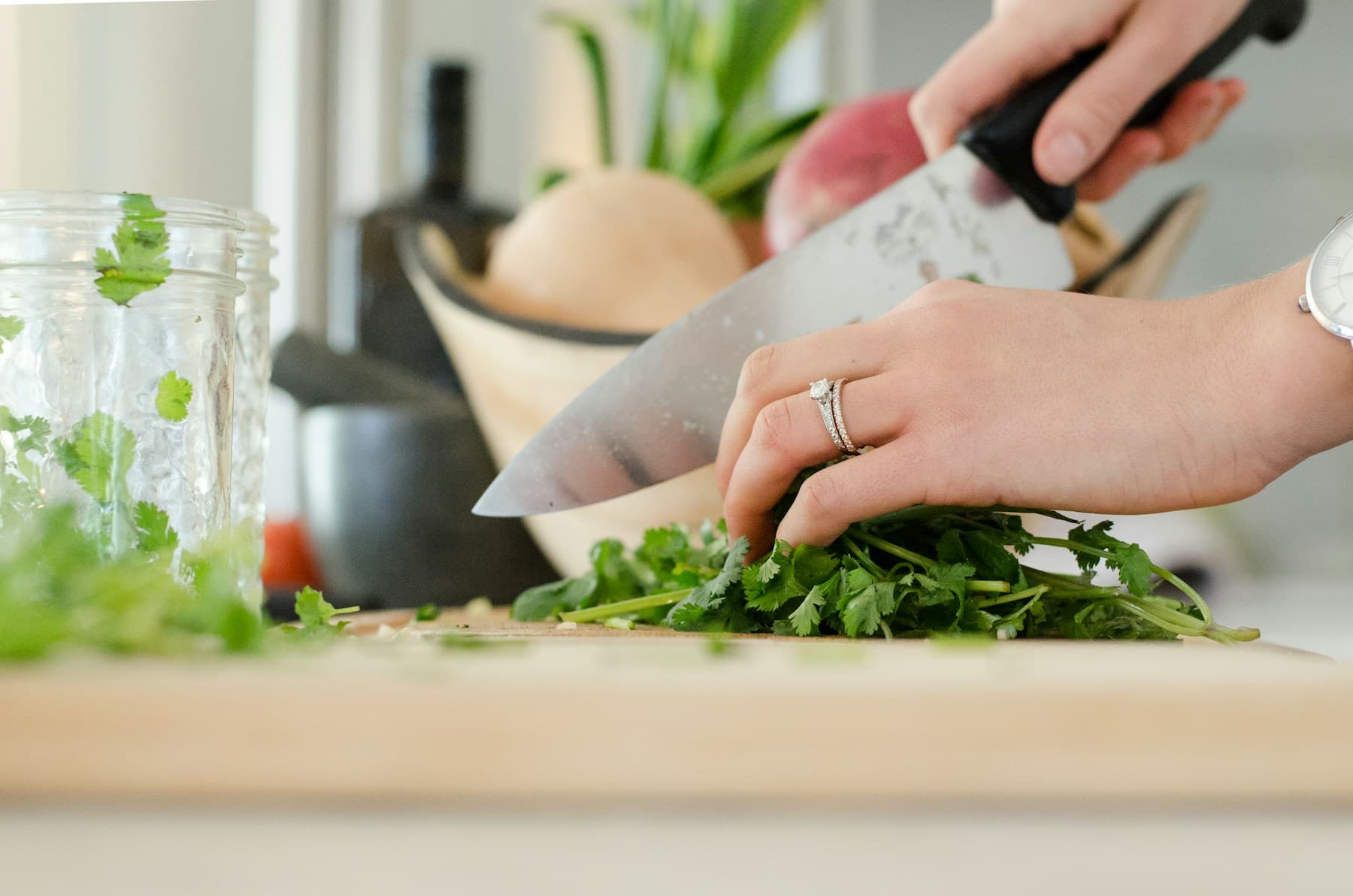 Hands preparing fresh herbs on a kitchen chopping board.